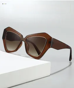 Detail view of geometric brown oversized sunglasses with gold metal trim and gradient lenses