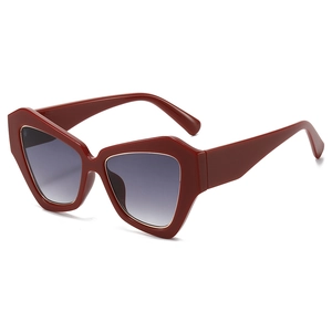 Fashionable oversized geometric red sunglasses with dark grey gradient lenses on white backdrop