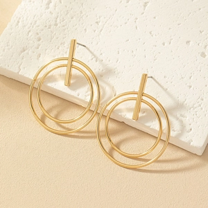 Detail of gold layered geometric circle earrings on a textured minimalist display