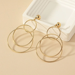 Golden multi-circle geometric drop earrings with triple concentric hoops on a neutral base