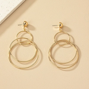 Macro detail of layered gold circular dangle earrings on a textured neutral background