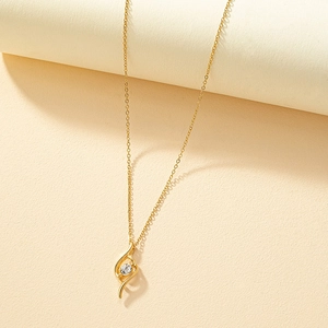 Collier minimaliste doré avec pendentif en S et zircon sur fond blanc texturé élégant