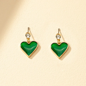Elegant gold heart earrings with green enamel and clear gemstone on textured background
