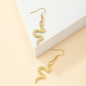Boucles d'oreilles serpent dorées avec cristaux pavés sur fond minimaliste moderne