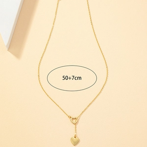 Collier Y doré avec pendentif cœur minimaliste et double cœurs sur fond beige sablé