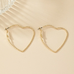 Textured gold heart-shaped hoop earrings with intricate metallic line detailing