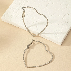 Close-up of silver heart hoop earrings featuring intricate textured engraved edges