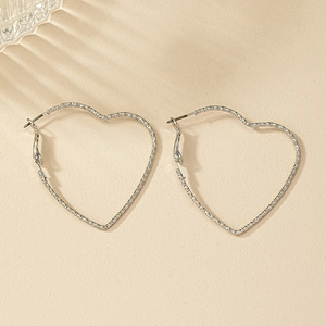Silver textured twisted rope heart-shaped large hoop earrings on beige background