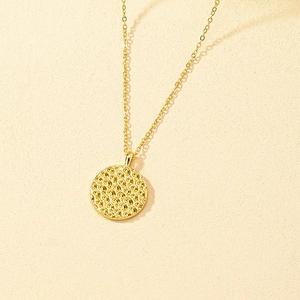 Minimalist gold plated necklace featuring a round coin pendant with honeycomb wave texture