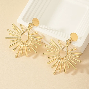 Modern gold sunburst drop earrings with geometric rays on minimalist display
