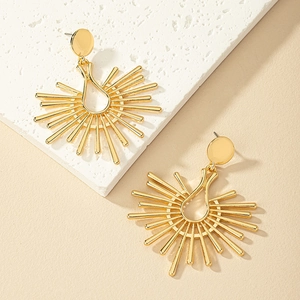 Macro detail of golden geometric sunburst earrings on minimalist stone pedestal