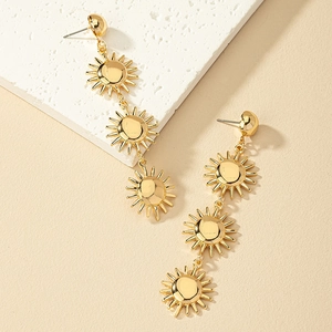 Three-tier gold sun drop earrings on stone and beige background for women fashion
