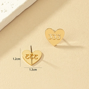 Puces d'oreilles cœur dorées avec découpe 333 sur fond minimaliste aux tons chauds