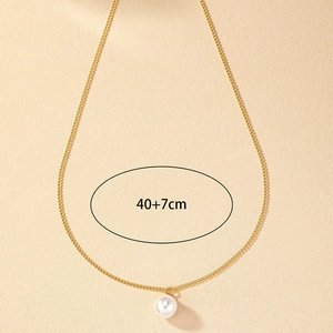 Elegant 40+7cm gold chain necklace with a single round pearl pendant on a beige surface
