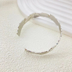 Dettaglio della texture martellata argentata su bracciale rigido regolabile