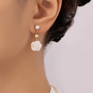 Elegant white rose drop earrings with pearls and gold beads on a female model
