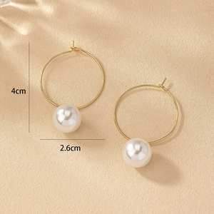 Détail de grandes boucles d'oreilles créoles dorées avec perles blanches et mesure 4cm