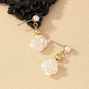 Elegant white resin rose earrings with pearl and gold metal beads on vintage background