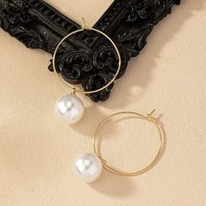 Élégantes boucles d'oreilles créoles dorées avec grandes perles blanches sur fond texturé