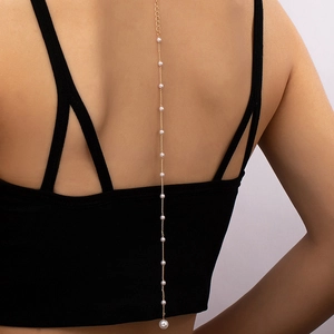 Chaîne de corps dorée élégante avec perles blanches sur une robe noire dos nu