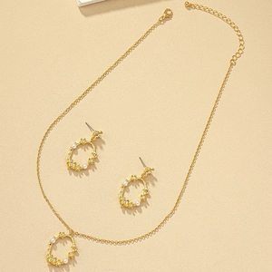 Parure de bijoux fleurs dorées avec perles et cristaux sur un fond de sable neutre
