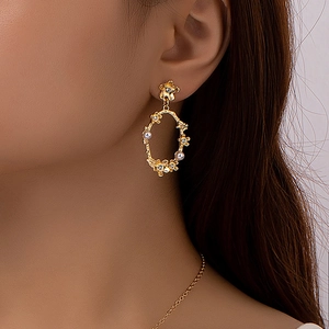 Boucles d'oreilles fleuries dorées élégantes avec perles et cristaux sur un mannequin