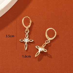 Macro detail of gold cross earrings with sparkling central zircon and floral镂空 patterns