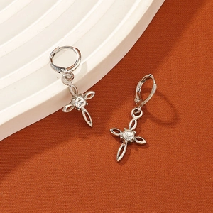 Detail of silver cross drop earrings with clear gemstone on a spiral display tray