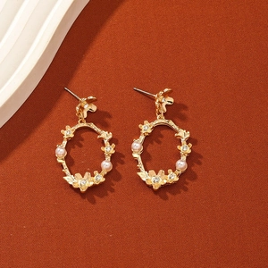 Boucles d'oreilles couronne ovale dorée avec perles blanches et cristaux sur fond chaud