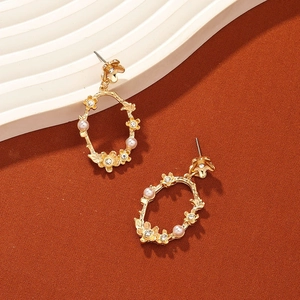 Élégantes boucles d'oreilles fleuries dorées avec perles et strass sur fond architectural
