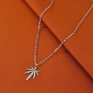 Silver maple leaf pendant necklace with link chain on an orange textured background
