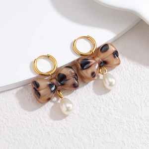Vintage leopard print bow earrings with drop pearls and gold-tone hooks on white surface