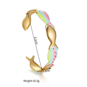 Détail des motifs de poissons en émail coloré sur un bracelet en acier doré 18 carats