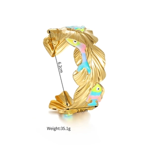 Detail view of 18k gold plated wide cuff bangle with colorful enamel fish and wave texture