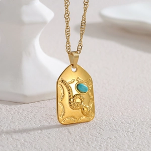 Vue macro du pendentif bouclier plaqué or 18k avec relief serpent et pierre turquoise