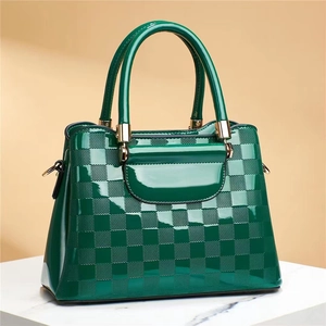 Detail of forest green crocodile texture leather bag with elegant gold metal hardware