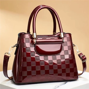 Close-up of wine red patent leather handbag with embossed checkered pattern and gold hardware