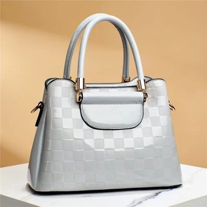 Detail of stone textured grid pattern handbag with gold hardware on marble base