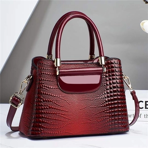 Close-up of burgundy crocodile pattern embossed leather bag with glossy finish and gold hardware