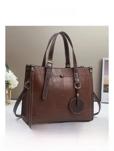 Detail view of brown patchwork leather tote bag with gold hardware and side pendant