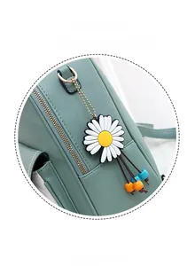 Detail of a white daisy bag charm with colorful beads on a green leather backpack