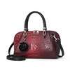 Détail d'un sac à main rouge et noir à motif autruche avec breloque florale