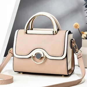 Close-up of contrast color handbag showing gold metal ring buckle and leather texture