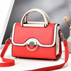 Detail of red and cream contrast leather handbag with golden circular metal clasp