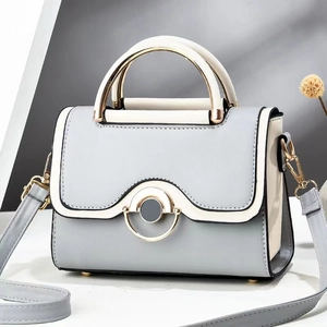 Modern two-tone crossbody bag in light blue and beige with golden metal handle
