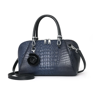 Navy blue faux crocodile texture handbag with black handles and a floral charm pendant