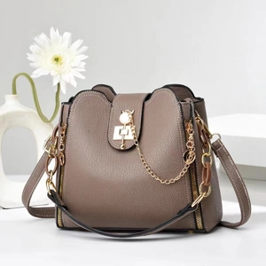 Taupe pebbled leather bucket bag with gold chain and cat-shaped metal lock accent