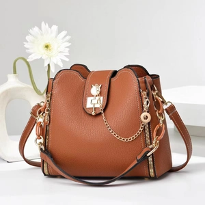 Brown elephant grain leather bucket bag with gold cat clasp on white background