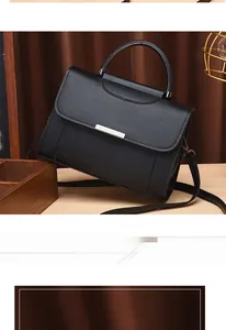 Detail of black textured synthetic leather handbag with silver clasp on a wooden surface