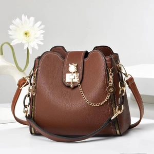 Macro detail of brown litchi pattern leather texture and golden cat-shaped lock on bucket bag